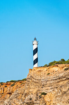 Ibiza, Balearic Islands, Spain: view of the Punta Moscarter Lighthouse (Faro de Moscarter), an active black and white striped lighthouse near Portinatx, on the northern coast of the island
