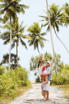 Happy young couple hug spin out of joy having fun together on sunny sandy pathway under tall coconut palm trees generic tropical island beach resort sunny summer day