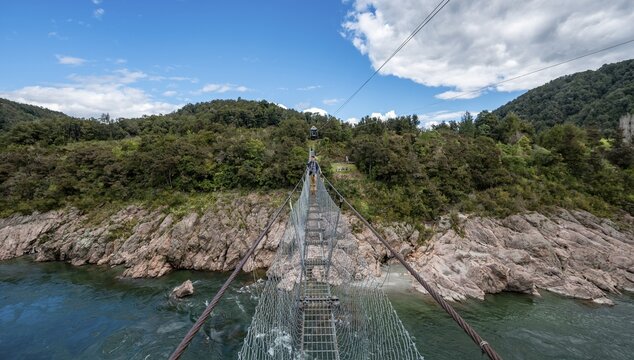 Young man on suspension bridge over Buller River, Buller Gorge Swing Bridge, Inangahua, West Coast, South Island, New Zealand