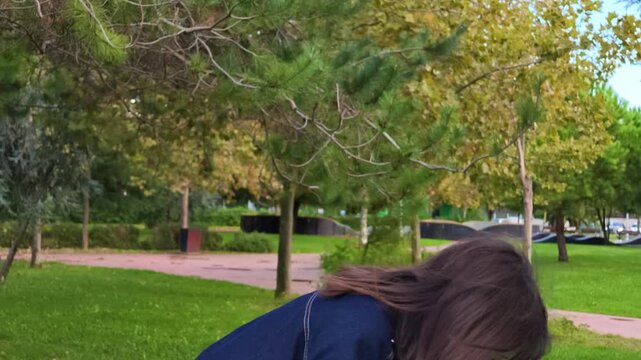 Young woman sneezing into her hand in a green park, allergy, cold and flu symptoms, hay fever, seasonal pollen allergies and sneeze concept outdoors, runny nose, health problem on a sunny spring day