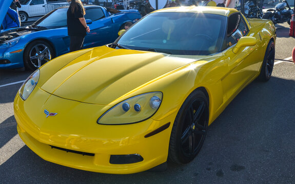 Vibrant yellow Chevrolet Corvette C6 coupe with sleek aerodynamic lines, exposed projector headlights, and black alloy wheels, highlighting iconic American V8 performance