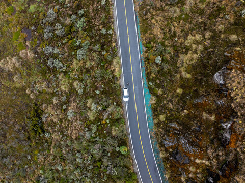 Aerial view of a car driving on a winding road through the rugged volcanic landscape of Nevado del Ruiz in Villamaria, Caldas, Colombia.