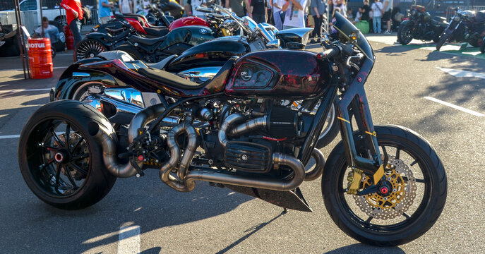 Futuristic custom Dnipro MT-10 motorcycle featuring girder front suspension, exposed boxer engine, custom exhaust, and wide rear tire at an outdoor event