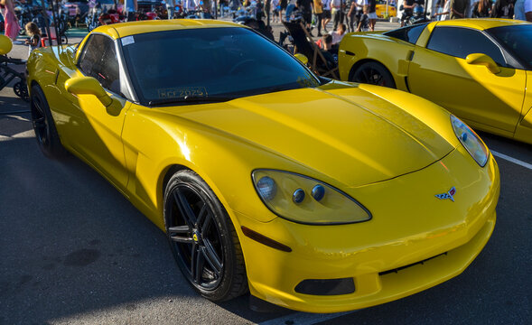 Vibrant yellow Chevrolet Corvette C6 coupe with sleek aerodynamic lines, exposed projector headlights, and black alloy wheels, highlighting iconic American V8 performance
