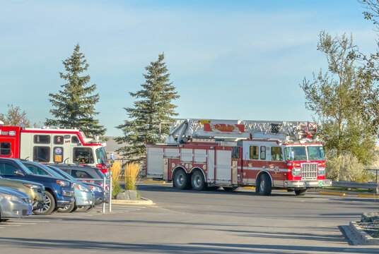 CALGARY, AB, CANADA - OCT 11, 2026. Side view of a Calgary Fire Department ladder truck driving in an outdoor parking lot.