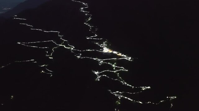 Glowing Himalayan night landscape featuring the steep, illuminated zigzag trails and spiritual infrastructure used by millions of Hindu devotees visiting the Vaishno Devi shrine.