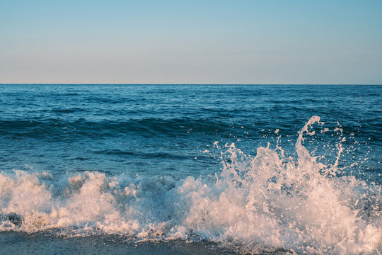 Water splash arcing from a breaking wave on a calm blue sea