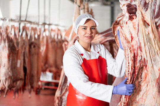 Female butcher showing beef chunk in meat storage