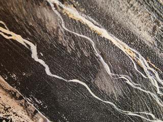 Close-up of dark, veined marble with golden and white streaks. Natural stone texture highlights luxury and elegance. Ideal for high-end design, architecture, or branding projects © mark_gusev