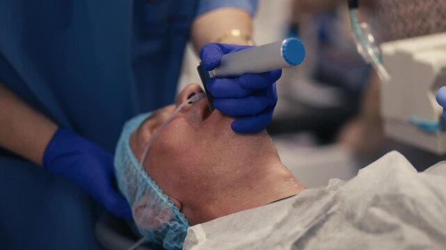 Medical staff inserting an endotracheal tube into a patient before surgery. Concept airway management, general anesthesia and surgical preparation.