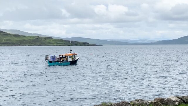 Small fishing boat on open sea surrounded by cloudy landscape, Isle of Mull, Inner Hebrides, Scotland, Great Britain