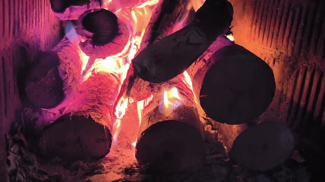 Burning logs and glowing flames in wood fire close up