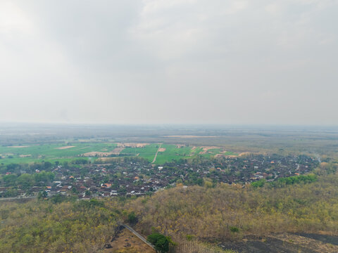 Aerial drone view of a rural village nestled among fields and dry teak forests in East Java Indonesia