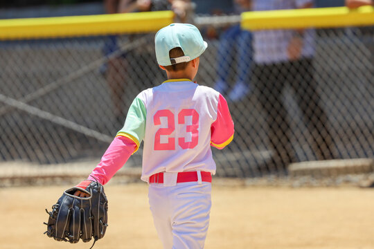 Youth Baseball Player in Vibrant Colorful Uniform with Glove on Hand Walking on Field during a game.