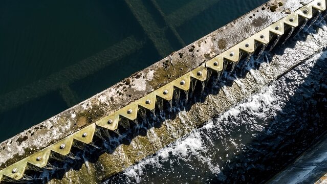 clarified water overflowing serrated V-notch weir plate in sedimentation clarifier tank 