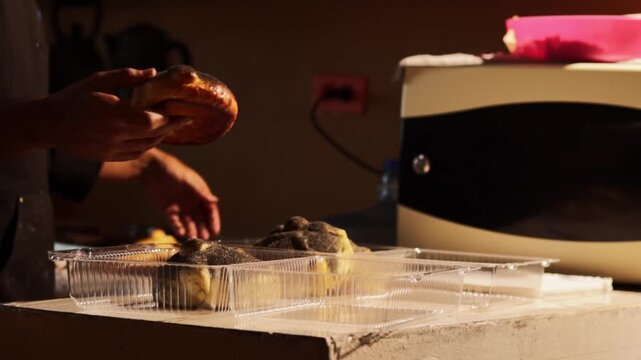 Baker packaging pan de muerto in plastic containers for day of the dead, traditional mexican sweet bread for dia de muertos, preparing food for the celebration