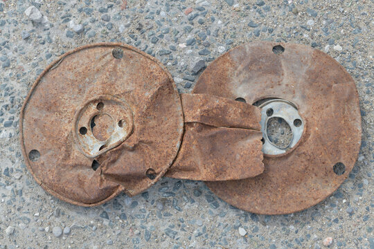 top-down view of a flattened old rusty metal spool on asphalt