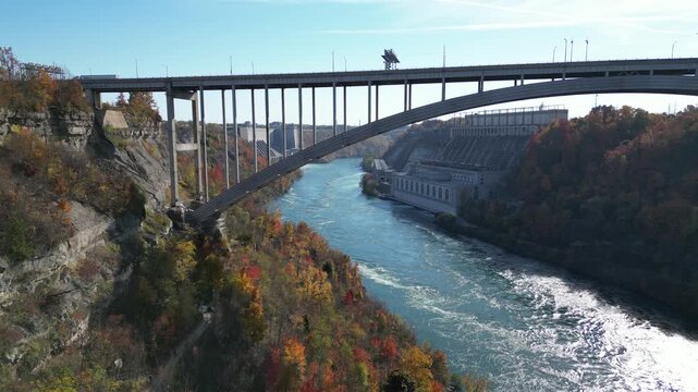 Aerial lifting up over the Niagara River and the international border crossing Queenston-Lewiston bridge between New York and Ontario, Canada with hydroelectrical power plants. Autumn in 2024.