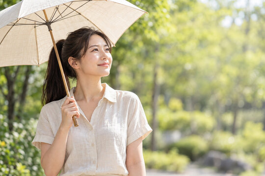 新緑の中で日傘を差す日本人女性