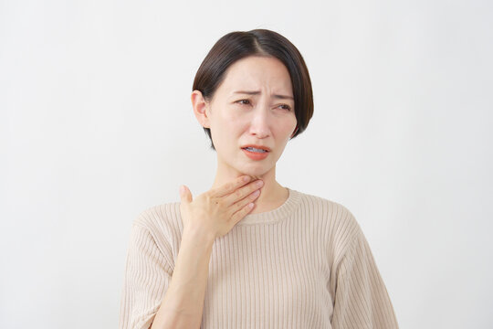 白背景で喉の痛みに苦しむ40代女性