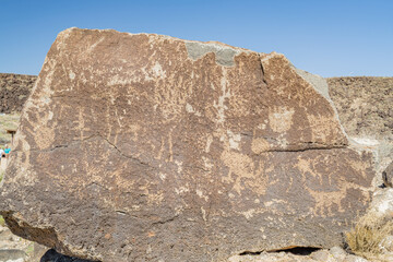 Petroglyphs on large boulder in desert landscape © Kit Leong