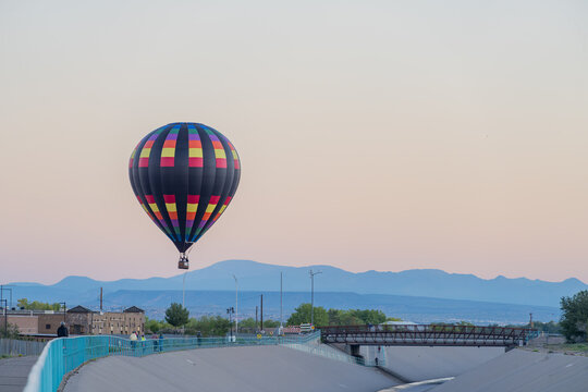 Colorful hot air balloon floating above bridge and mountains