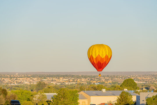 Hot air balloon floating over desert landscape and town