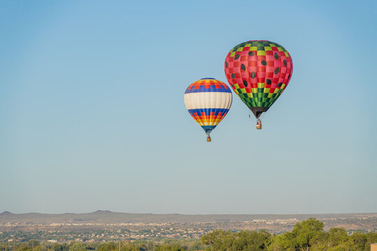Two colorful hot air balloons floating above desert landscape
