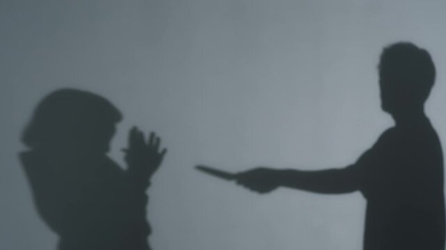 Silhouette of a man holding a knife to a woman