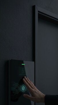 Hand touching biometric fingerprint scanner terminal for access granted on black door wall vertical