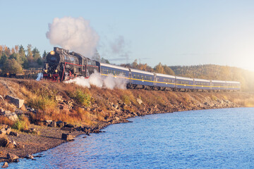 Retro steam train moves along the lake. © serjiob74