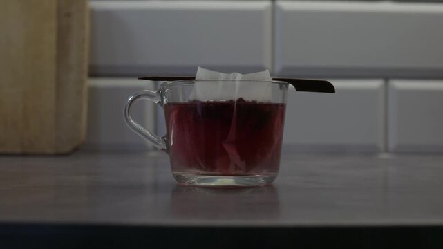 Glass Cup of Red Tea with Tea Bag on Kitchen Counter