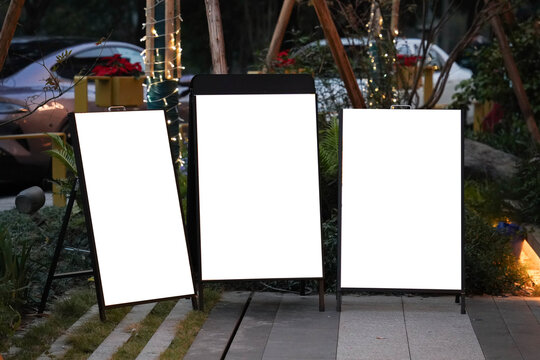 Three blank white outdoor advertising stand or sandwich boards mock up template placed by an indoor building