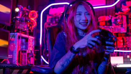 Gamer using joystick controller for virtual tournament plays online video game with computer neon lights dark room, woman wear gaming headphones playing live stream esports games console © sorapop