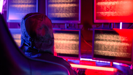 Woman hacker wear hood sit front computer typing on keyboard hacking servers in neon light, Gamer woman streaming game online dark room, Female hacker breaks into data center © sorapop