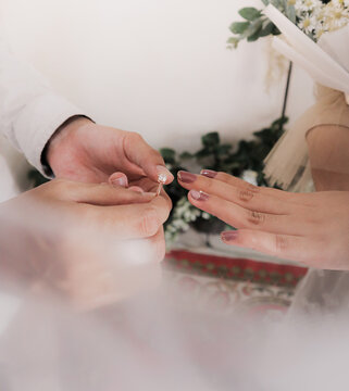 Close-up of couple&rsquo;s hands during wedding ring exchange, placing a ring on a finger