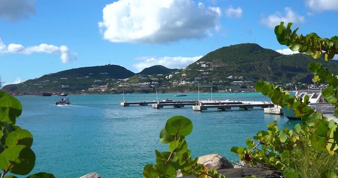 Boat dock framed by foliage with Philipsburg town in distance, Sint Maarten