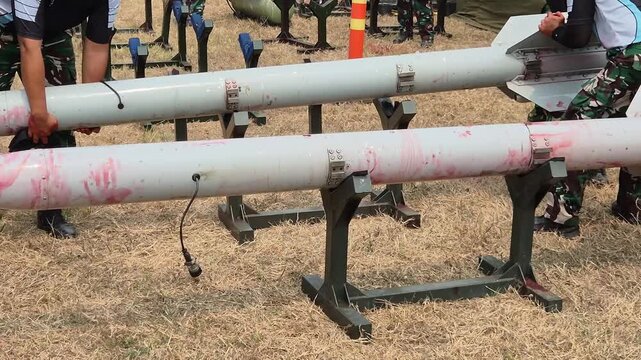 Military air to air missiles on display stand with red marks in outdoor base.