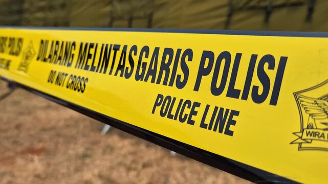Yellow Indonesian police line tape with DO NOT CROSS and POLICE LINE text.
