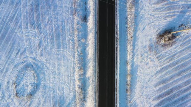 Surreal drone flight creating a mirror effect over a snowy road splitting into a Y-junction