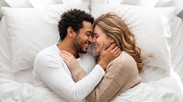 Happy young interracial couple lying together in bed and sharing an intimate tender moment.