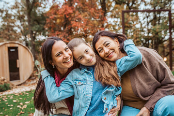 Fototapeta premium Mother, grandmother and granddaugter standing in autumn garden.