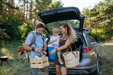Naklejka premium Family unloading luggage from car and setting up a campsite.