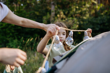 Naklejka premium Dad and kids setting up tent together during summer camping trip.