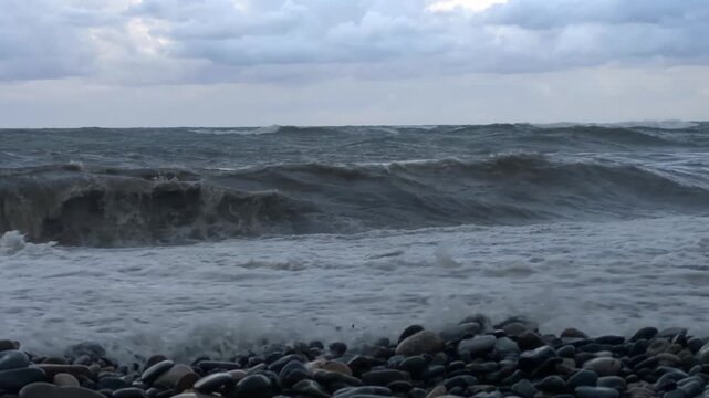 Low angle waves crashing onto stony beach, showing choppy Black Sea water surging across the pebble shoreline in Batumi, Georgia, for coastal weather reports, tourism campaigns and nature footage