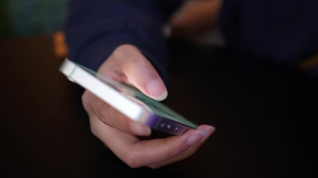Woman using a smartphone while seated at a caf&eacute;, representing modern lifestyle and digital connectivity.  Night View.