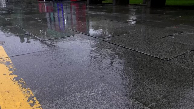 Rainwater covers an urban roadway beside buildings, providing footage for stormwater management, street maintenance planning, weather coverage and city drainage communication after heavy rainfall