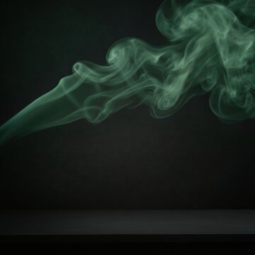 Wispy green smoke swirls rising above a dark horizontal surface against a black background