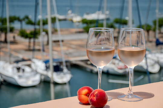 Glasses of cold rose wine and view on Cap d'Agde marina with boats, Mediterranean Occitanie, Languedoc wine production, summer vacation destination and tasting of regional wines