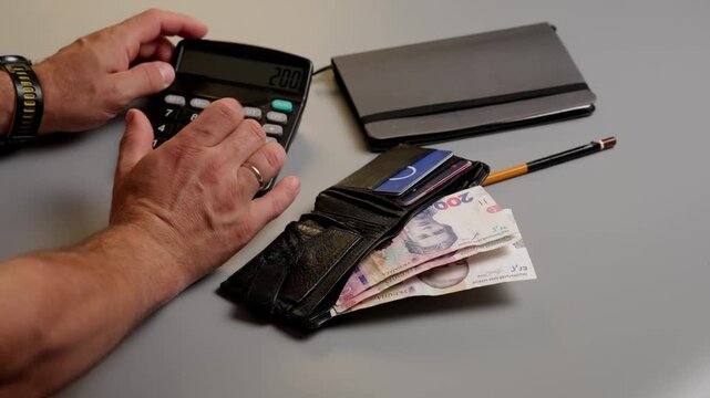 Calculating a budget with a calculator notebook and wallet nearby